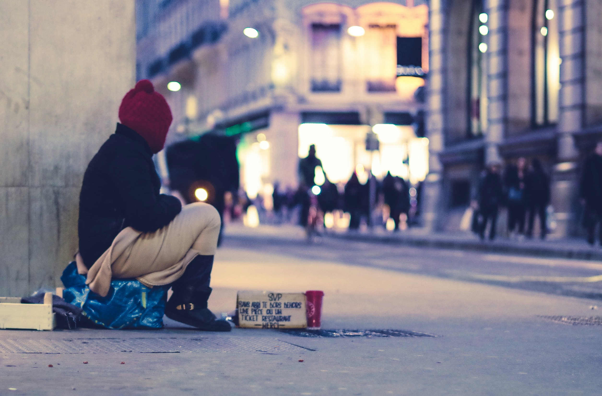 A homeless person looking out, sitting on a makeshift blue stool.